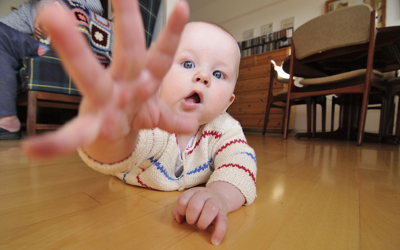 Baby på gulv - rækker ud efter fotograf