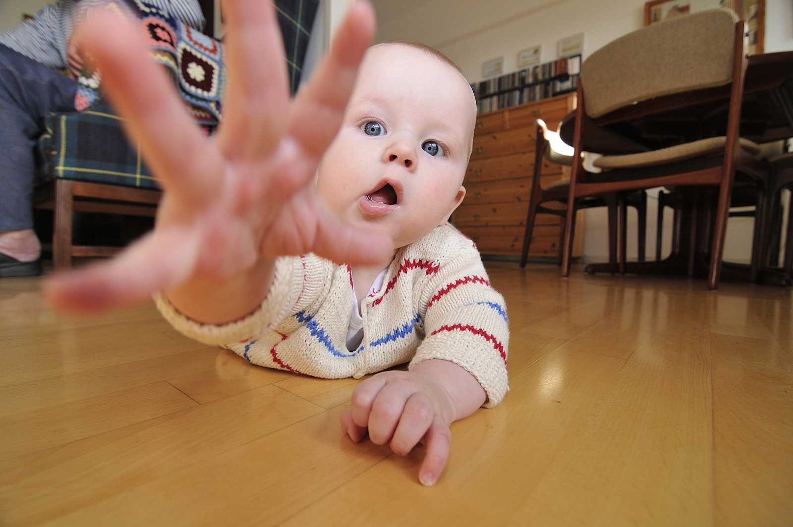 Baby på gulv - rækker ud efter fotograf