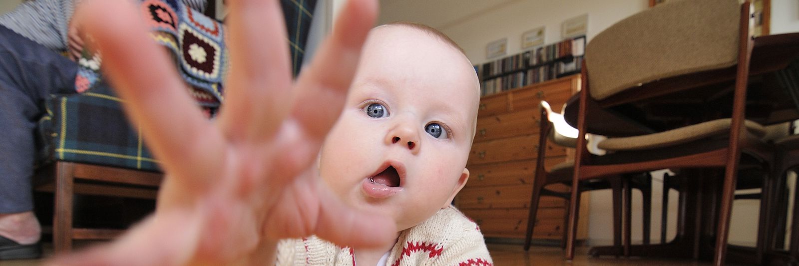 Baby på gulv - rækker ud efter fotograf