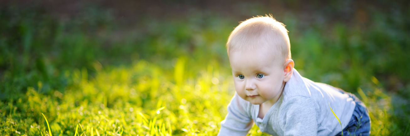 Dreng kravler i græs